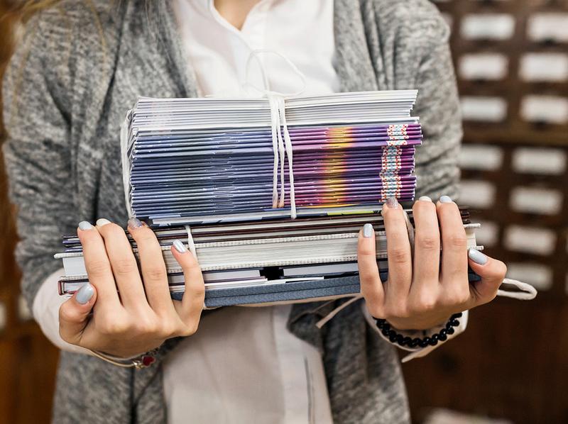 Gros plan sur une lourde pile de catalogues d'entreprise imprimés en couleurs et reliés, mettant en avant la qualité de finition.